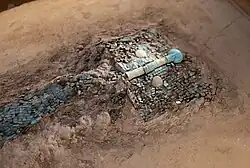 The head of a large turquoise and jade sculpture of a dragon embedded within a block of earth