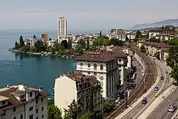 A daytime view of mostly brown-roofed buildings and a railway near the shores of Lake Geneva in Montreux, Switzerland