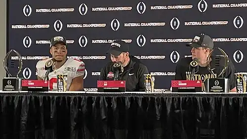 Football players and coaches giving a press conference