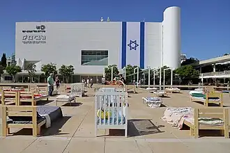 The "Empty Beds" installation in HaBima Square (Culture Square) in Tel Aviv, where empty beds are displayed, including children's beds and cribs, which represent the abductees.
