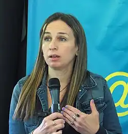 a photo of Waldman at the 2024 Gaithersburg Book Festival. Waldman is holding a microphone and speaking.