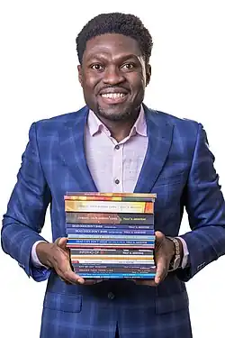 Tolu Akinyemi, aka The Lion of Newcastle, holding some of his books.