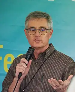 A photo of Taylor at the 2024 Gaithersburg Book Festival. Taylor is holding a microphone and speaking.