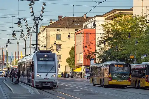 White and red tram and yellow busses
