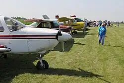 several planes parked on a grassy field as a man walks by
