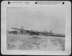A black and white photograph of a plane docked at an airfield