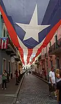Calle de la Fortaleza leading to the palace with a canopy of the Monoestrellada (Monostarred) flag of Puerto Rico