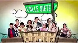 An image of the cast, with a building and a street sign. The series title is displayed on the upper center of the image, over the green street sign.