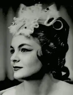 Publicity profile shot of a young woman in heavy operatic makeup and headgear.