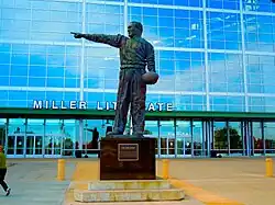 A statue on a pedestal of a man pointing and holding a football