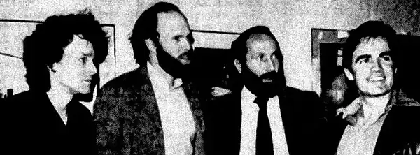 Photograph of four men standing indoors