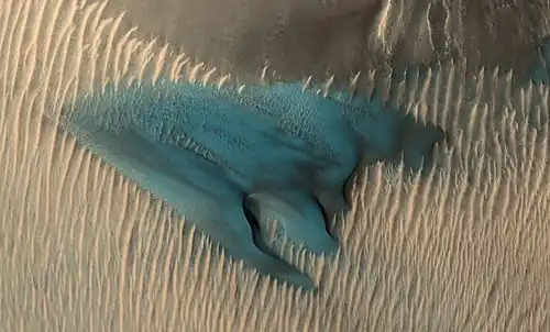 A dune on Mars appears in false colors blue. In false colour colours yellow to blue represent warmer to colder regolith.[55]