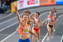 Photo of Femke Bol holding one hand in the air while finishing ahead of the other competitors
