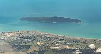Aerial photo with land at the bottom and a large island separated from the mainland by a small channel.