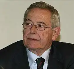 caucasian male, 60s, wearing a suit and spectacles