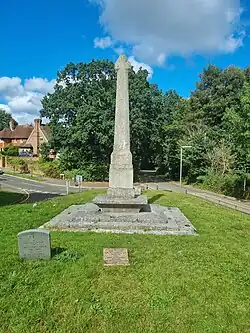 Stone cross on a patch of grass overlooking a fork in the road