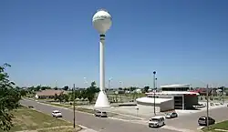A white water tower is surrounded by eco-friendly buildings in this aerial shot.