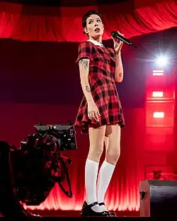 Halsey singing into a microphone with her hand raised
