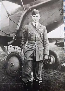 Hugh Eliot in uniform, standing in front of an aircraft