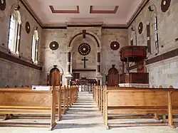 dark wood pews, altar and private royal pew carved with floral motifs and hung with red satin