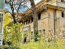 The south and east elevations of the Heller House, which are made of brick. There are trees in the foreground