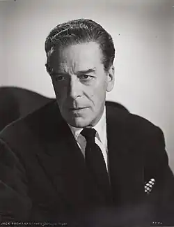 middle-aged, clean shaven white man with full head of hair, dressed in lounge suit