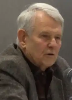 Head shot of white-haired, serious-looking male.