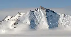 A large icy mountain with a rocky, ice-free peak rising out of a glacier