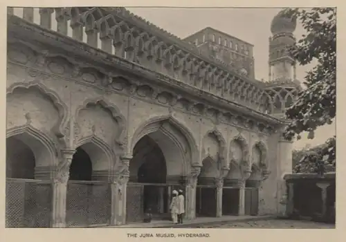 Black-and-white image of a building with arched entrances. Two people are seen entering through one of the entrances.