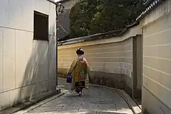 A maiko walking along a narrow street.