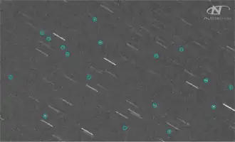 A telescope image showing stars as streaks and Kosmos 1408 debris as circled dots