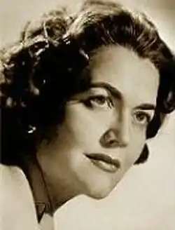 Three-quarter profile, sepia, publicity headshot, film-star-style, of a dark-haired woman with heavy makeup and bouffant hairdo.