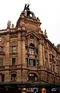Red sandstone frontage in the ornate and French Renaissance style and with a theatrically Baroque skyline. The wording "London Hippodrome" face to the front on the upper level, also in red sandstone