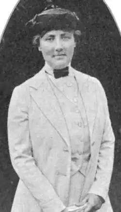 Black & white photo of woman wearing a light suit and a dark hat