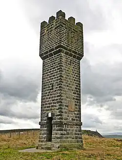 A brick tower, about 11 meters high, against a cloudy background. The tower has a square base. At the top, there are 3 battlements visible.