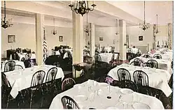 Large room with pillars and chandeliers with tables and narrow chairs