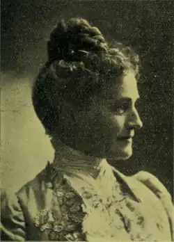 B&W portrait photo of a woman with her hair in an up-do, wearing a light-colored blouse.