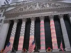 The columns of the NYSE lit up for Christmas, with the American flag being projected onto the colonnade