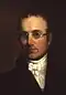Portrait of Nathan Lord with glasses, wearing a dark coat and white cravat.