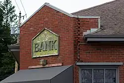 A portion of a brick building, with an aged sign saying "Bank".