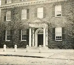 Image of the doorwayat 13 Brown Street in Providence, RI. Vines grow on the portico and the exterior of the brick building. A fanlight is above the open doorway.