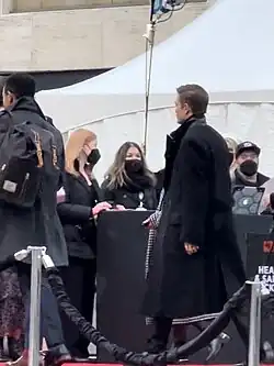 Robert Pattinson walking in a trench coat at Lincoln Center in New York City.