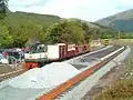 Northerly view of Rhyd Ddu station in the final stages of construction on 26 May 2003. Diesel loco Conway Castle hauls a PW train with a tamping machine in the background.