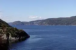 A very wide river flows between low lines of hills.