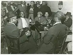 Photo of patrons sitting around a table in a juke joint in Clarksdale, Mississippi, in 1939