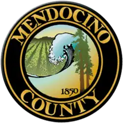 The county's official seal, in chief two redwood trees and the numbers '1850', a breaking wave on the Pacific Ocean and a vineyard set in relief, bordered by a dark brown circle with the words 'Mendocino County' appearing within the border in gold block letters
