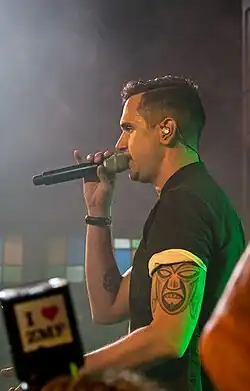 Jan Dettwyler wearing short-sleeved shirt, holding a microphone, with earphones