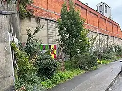 St. Anne's Road Pocket Park in Dublin, Ireland occupies a sliver of land, backed by the high wall of Drumcondra railway station.