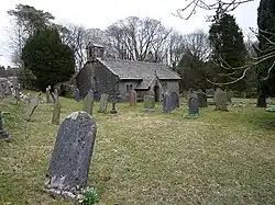 A grassed graveyard in the foreground with a small one-storey chapel in the background