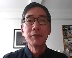 Headshot of Honda, who wears glasses, in an indoors environment